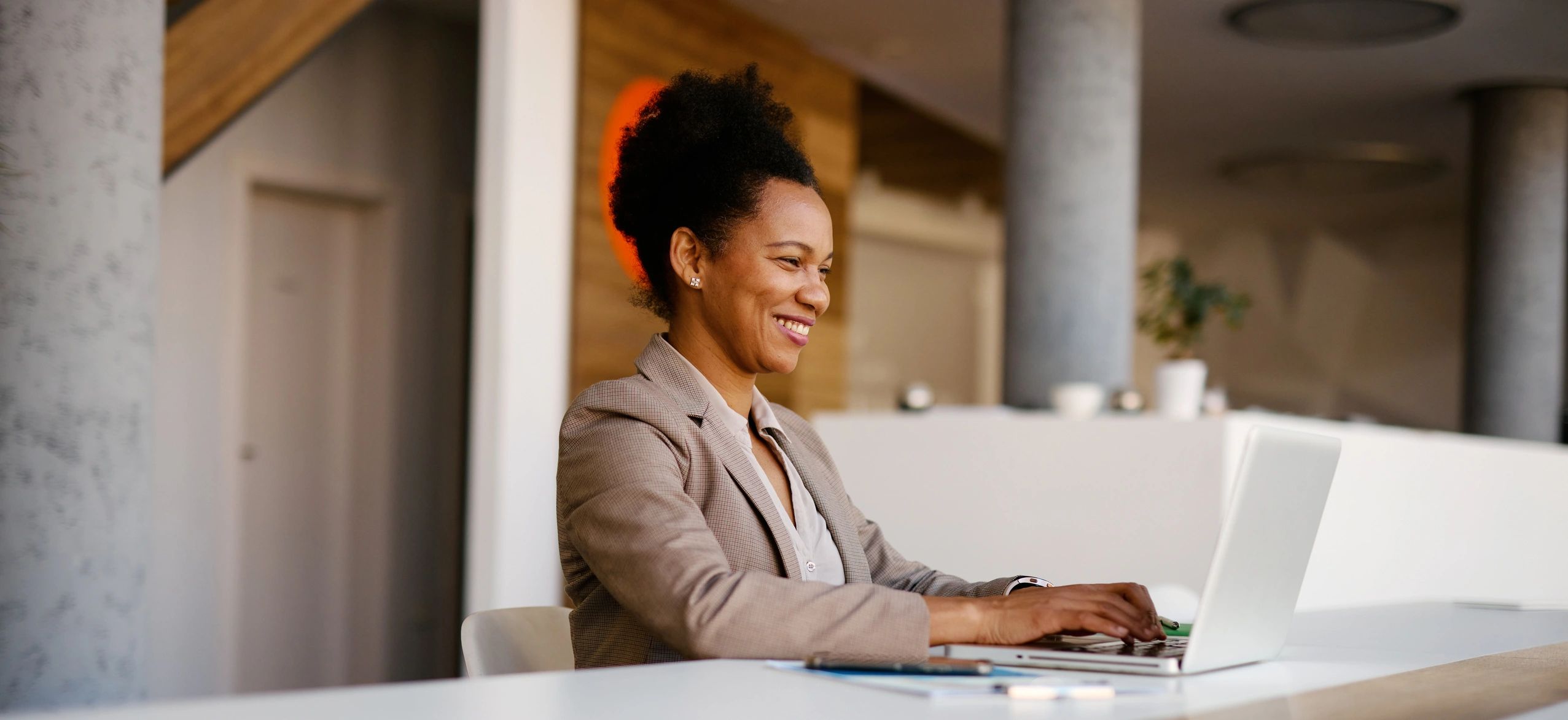 Smiling businesswoman working on a laptop in a modern office